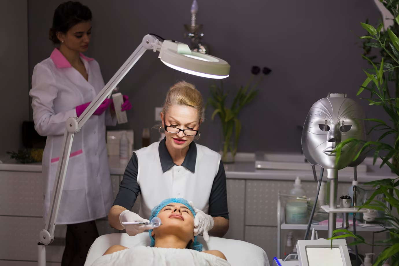 Profissional de estética atendendo uma cliente mulher deitada em uma mesa.