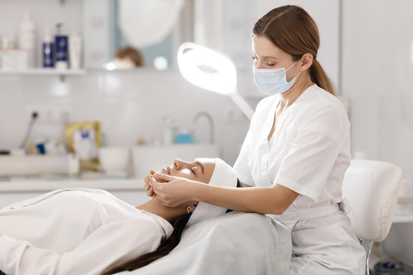 Profissional de estética fazendo tratamento em uma mulher deitada em sua maca